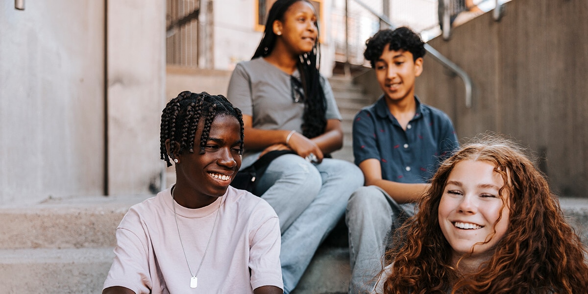 Multiracial group sitting on outdoor steps, talking with each other